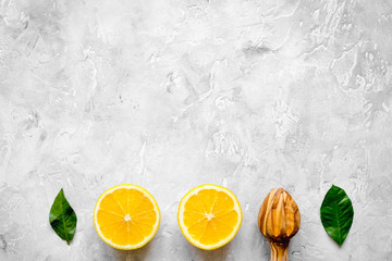 cut oranges and wooden juicer on concrete background top view