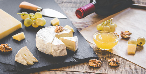 bottle of red wine, appetizers and corkscrew on wooden background