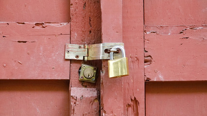  Close up view of a paddle lock and latch fastening an old and rotted wood door