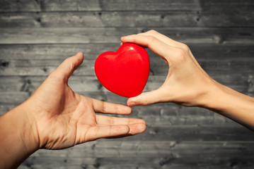 Fototapeta premium Giving love and donating concept. Hand passing heart to another. 