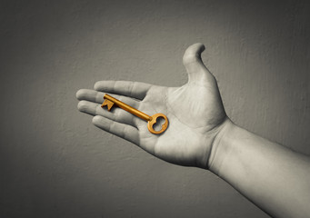Hand holding a golden key. 