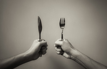 Time to eat. Hand holding knife and fork. 