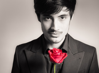 Handsome man holding a single red rose. Romantic valentines gift concept. 