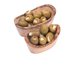 Green colossal olives hand stuffed with garlic gloves in olive wood bowl isolated on white background