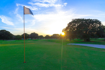 Obraz premium White golf flag on the green during the beautiful sunset in Florida