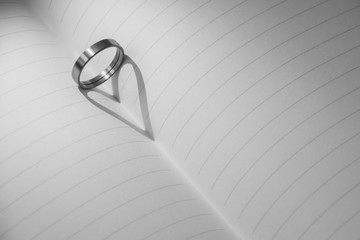Ring casting a heart shadow onto book, Black and white tone