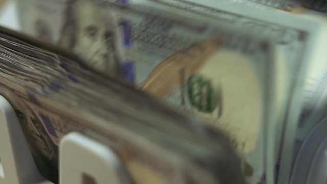 Money counting machine counts 100 dollar bills. Close up shot