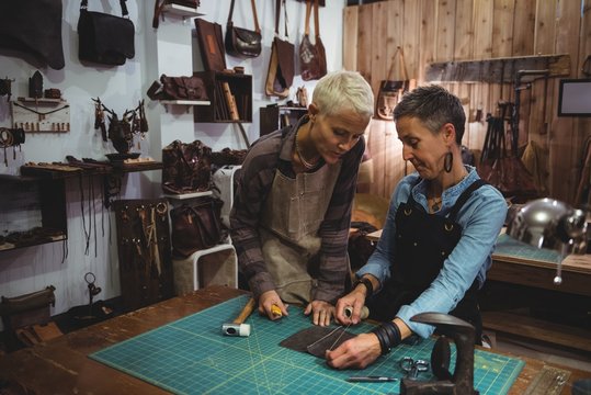 Craftswomen discussing over a piece of leather