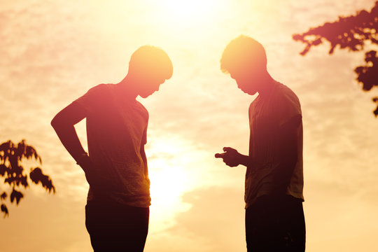 The silhouette of two young men conflict on sunset.