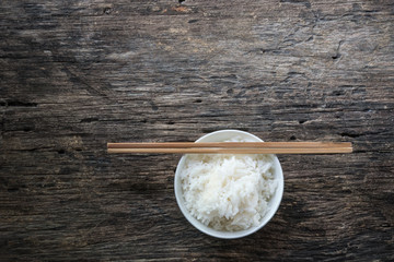 Jasmine rice in the bowl and chopsticks on wooden.