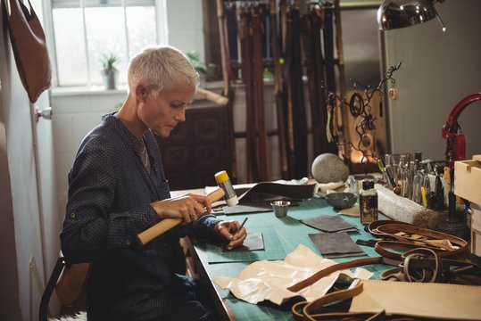 Craftswoman hammering leather