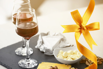 Glasses of red wine with snack on table. Festive ribbon bow on background. Holiday celebration concept.