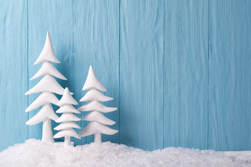 Christmas background with white christmas trees and snow, blue wooden background