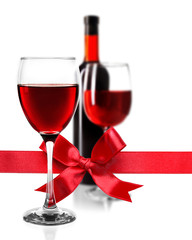 Glass of red wine with festive ribbon bow on white background. Holiday celebration concept.