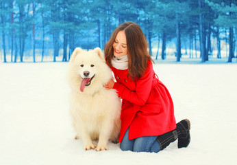 Happy young woman owner with white Samoyed dog winter on snow