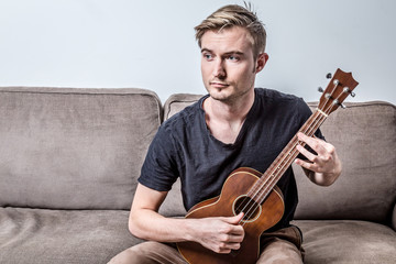 Obraz premium handsome man playing ukulele or small guitar with worry feeling