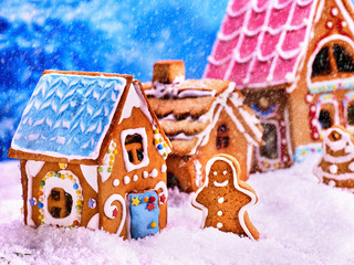 Exhibition gingerbread houses in snow with gingerbread man and gingerbread Christmas tree in snow. Christmas food concept.