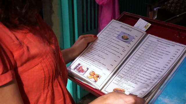 Beautiful woman sees the menu and selects a meal at an outdoor restaurant. Order drinks to takeaway.