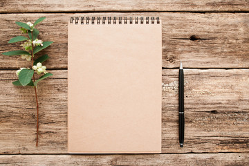 Vintage sketchbook with pen and flower mockup. Top view on blank brown notebook on old brown background, flat lay, free space. Art, craft, inspiration, memory , rustic, business, planning concept
