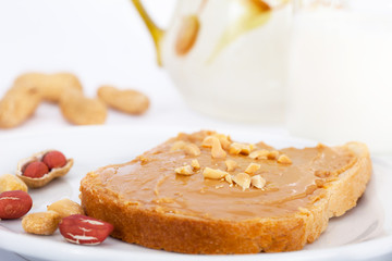 Creamy peanut butter on bread toast and milk for breakfast
