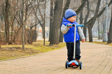 the boy goes on the scooter on a path