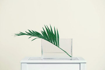 Green branch in vase on light background