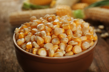 Corn seeds in bowl on wooden table, closeup