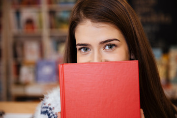 Portrait of a young woman covering her face with book