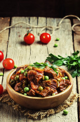 Ragout with beef, carrots, green peas and tomatoes, old wooden b