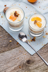 Fresh homemade dessert with biscuits, yogurt, tangerines and walnuts, served in a glass