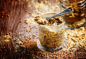 Mustard sauce with grains, old wooden background, selective focu