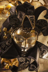 Venetian carnival mask. Golden and black with bells and tinsel over golden background, Venice
