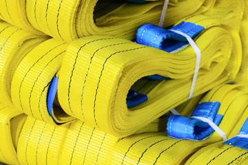 Yellow nylon soft lifting slings stacked in piles.