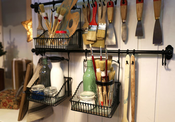 Some brushes with other needed stuff for repairing and making arts. They are located on the wall which is wooden