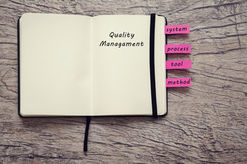 book for notice with words quality management, system, process, tool and method on the wooden background.business concept