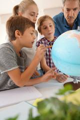 Teacher with kids in geography class looking at globe