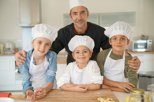 Portrait of happy pastry chef together with kids in cooking class
