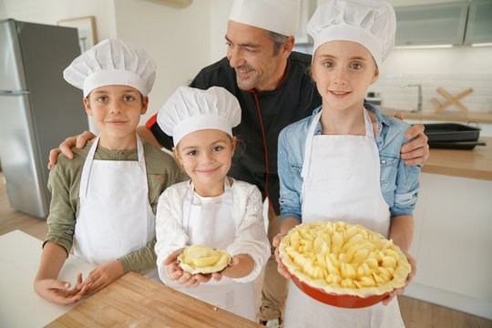 Portrait of pastry chef with pupils holding apple pie