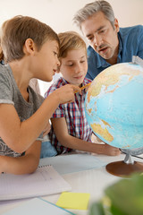Fototapeta premium Teacher with kids in geography class looking at globe
