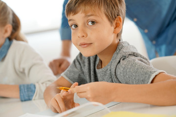 Portrait of pupil in school class taking notes during writing lesson