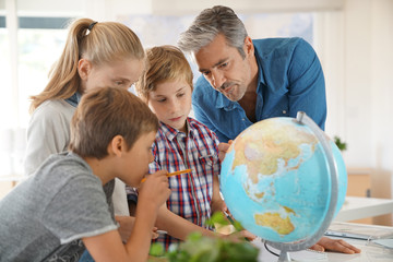 Teacher with kids in geography class looking at globe