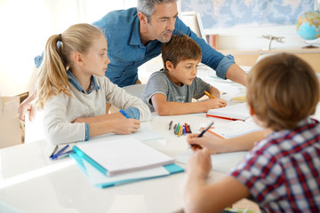 Teacher with kids in class giving writing lesson