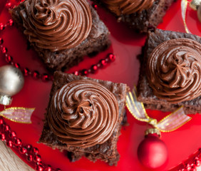 Chocolate brownie cake with cream on red festive Christmas background, top view, closeup - holiday dessert