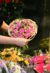 A woman holding a bouquet of roses wrapped in paper