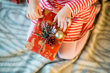 Little girl unpacks a decorated Christmas gift box. Close-up. The concept of Christmas