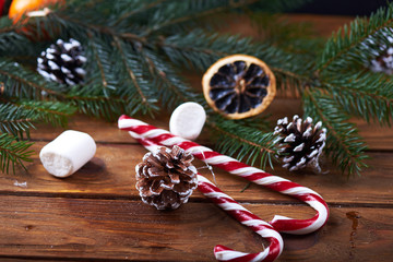 Christmas background of branches, cones, marshmallow and candy canes against a wooden background