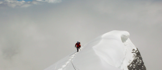 a mountain climber on an exposed summit ridge in the Swiss Alps