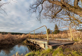 pedestrian bridge through a stream in the marshland autumn cloudy weather