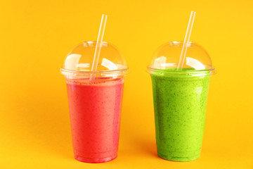 Delicious kiwi and strawberry milkshakes on yellow background