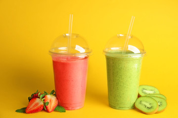Delicious kiwi and strawberry milkshakes on yellow background